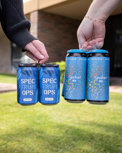 Two hands holding four-packs of Spectrum cans with custom wrap labels