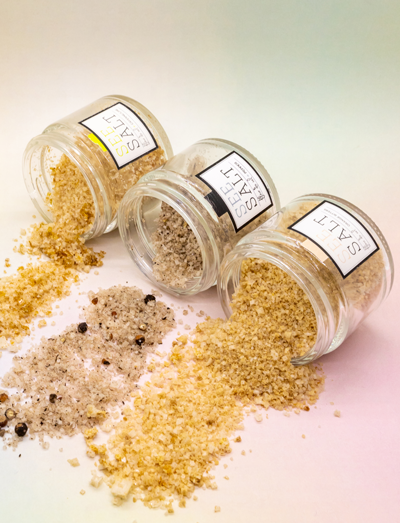 Three labelled glass spice jars tipped over with seasoning blends spilling out